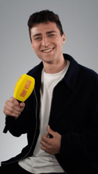 Joven sonriente sosteniendo un micrófono amarillo en un fondo gris