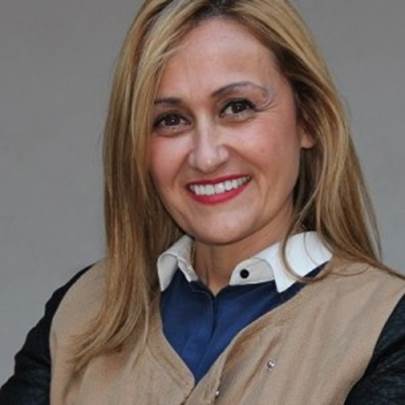 Retrato de una mujer sonriente con cabello rubio y blusa clara